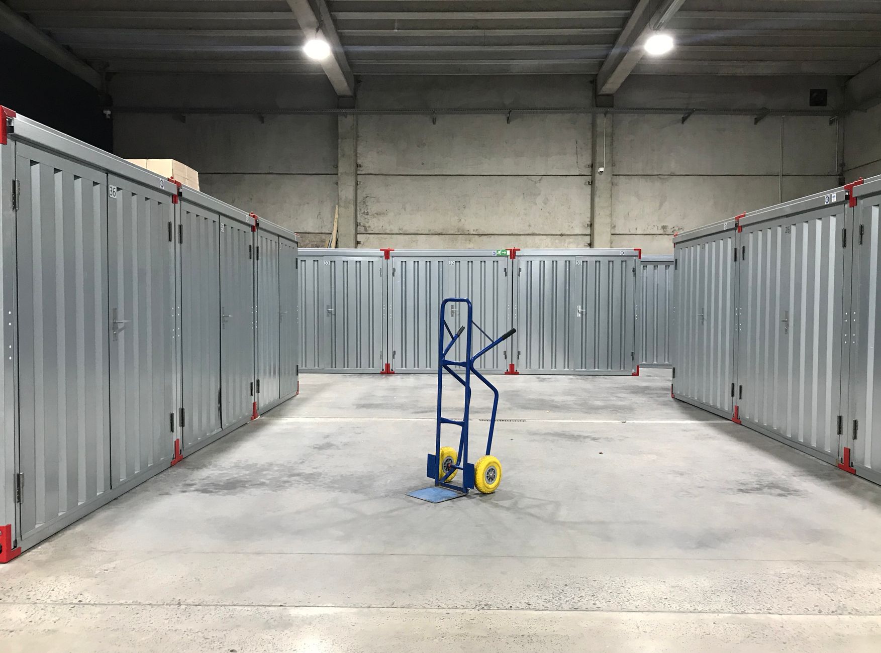 Clean indoor storage facility with steel units and a hand truck